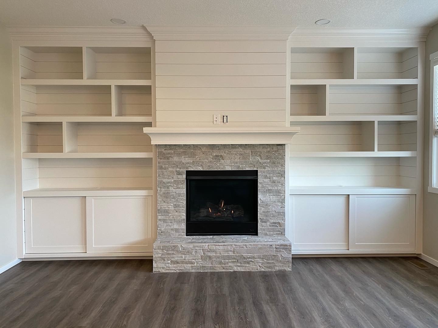Built-in shelving unit with concealed sliding cabinet doors on the bottom. 