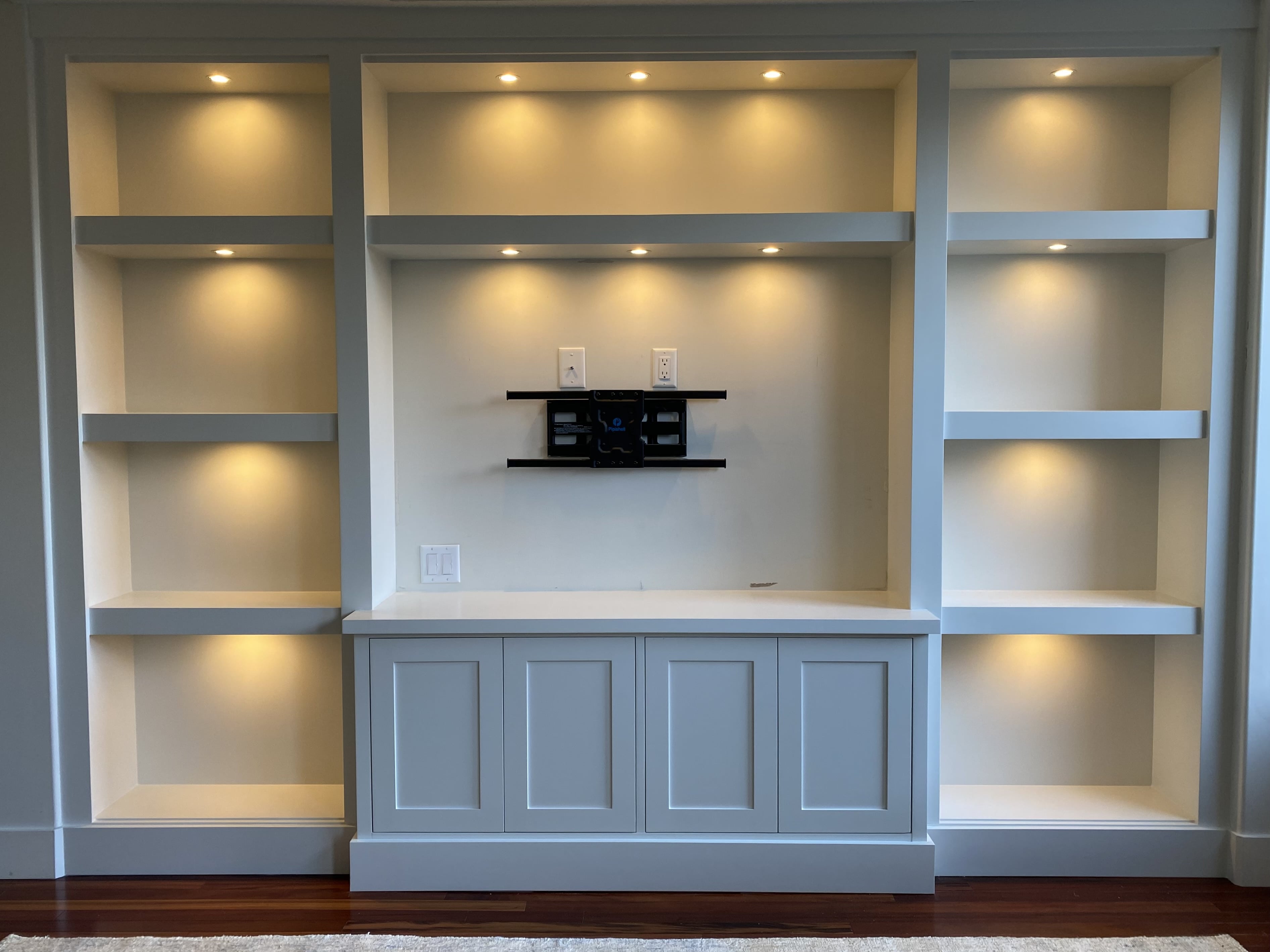 Built-in entertainment unit with a lower cabinet centered between two large shelves. 
